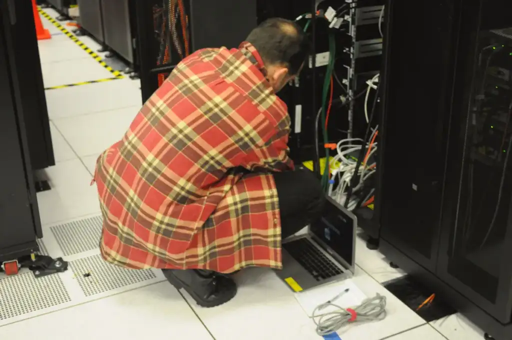 ChatGPT Dots: Technician with laptop working on server rack at NERSC