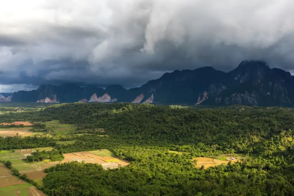 severe thunderstorm watch: Sunlight and stormy sky over the mountains and paddy fields in Vang Vieng, Laos